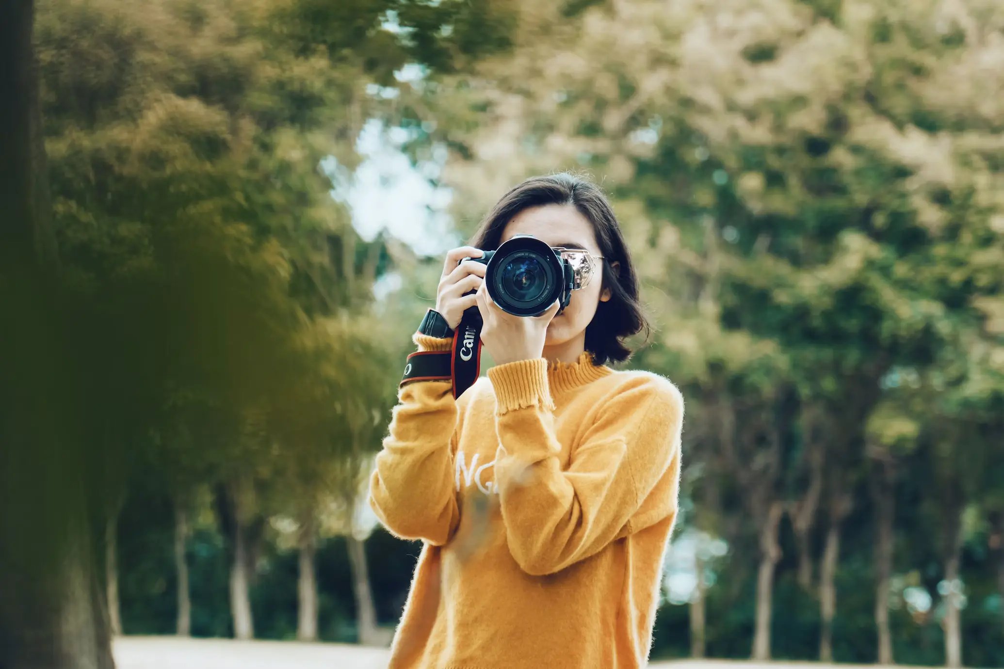 Woman holding a DSLR camera, representing authentic professional photography in the age of AI