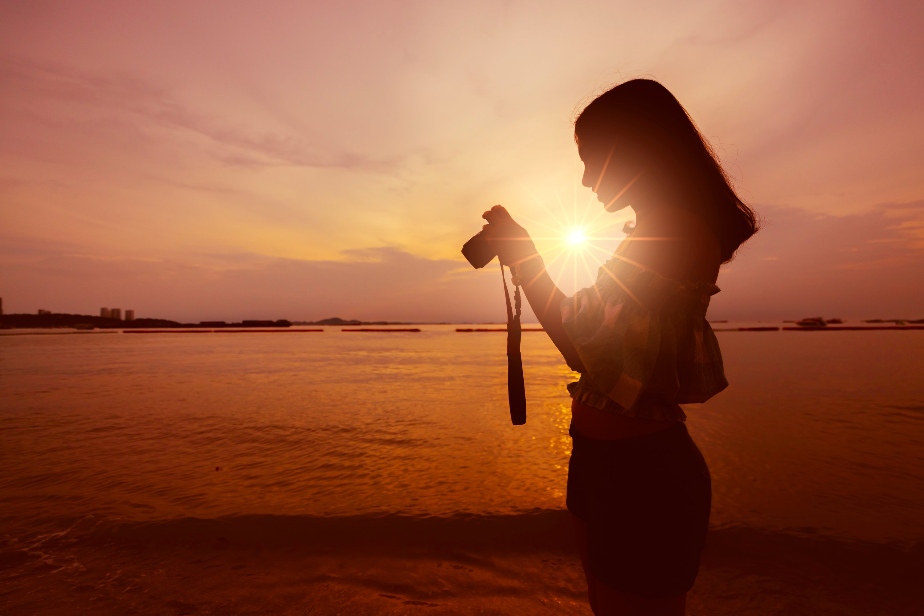 Asian woman taking photo on beach